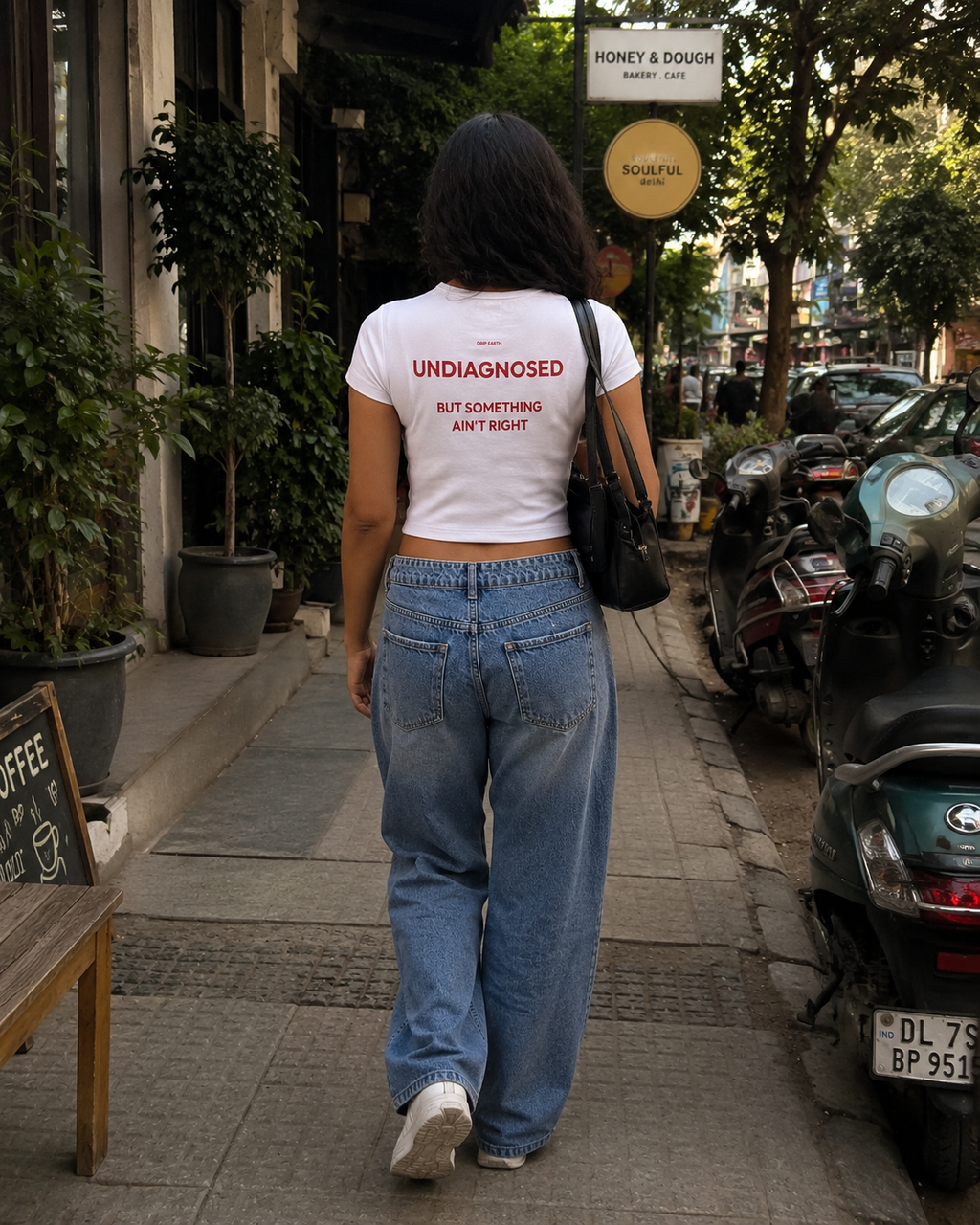 White Drip Earth female baby tee with UNDIAGNOSED graphic - lifestyle streetwear shot