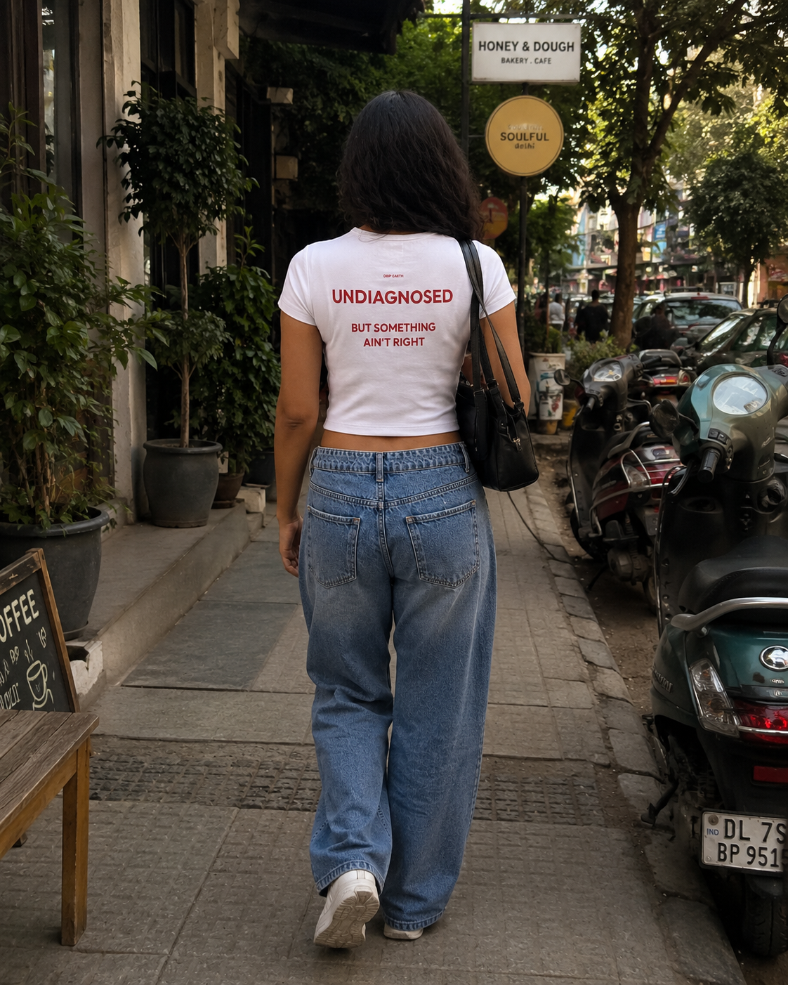 White Drip Earth female baby tee with UNDIAGNOSED graphic - lifestyle streetwear shot